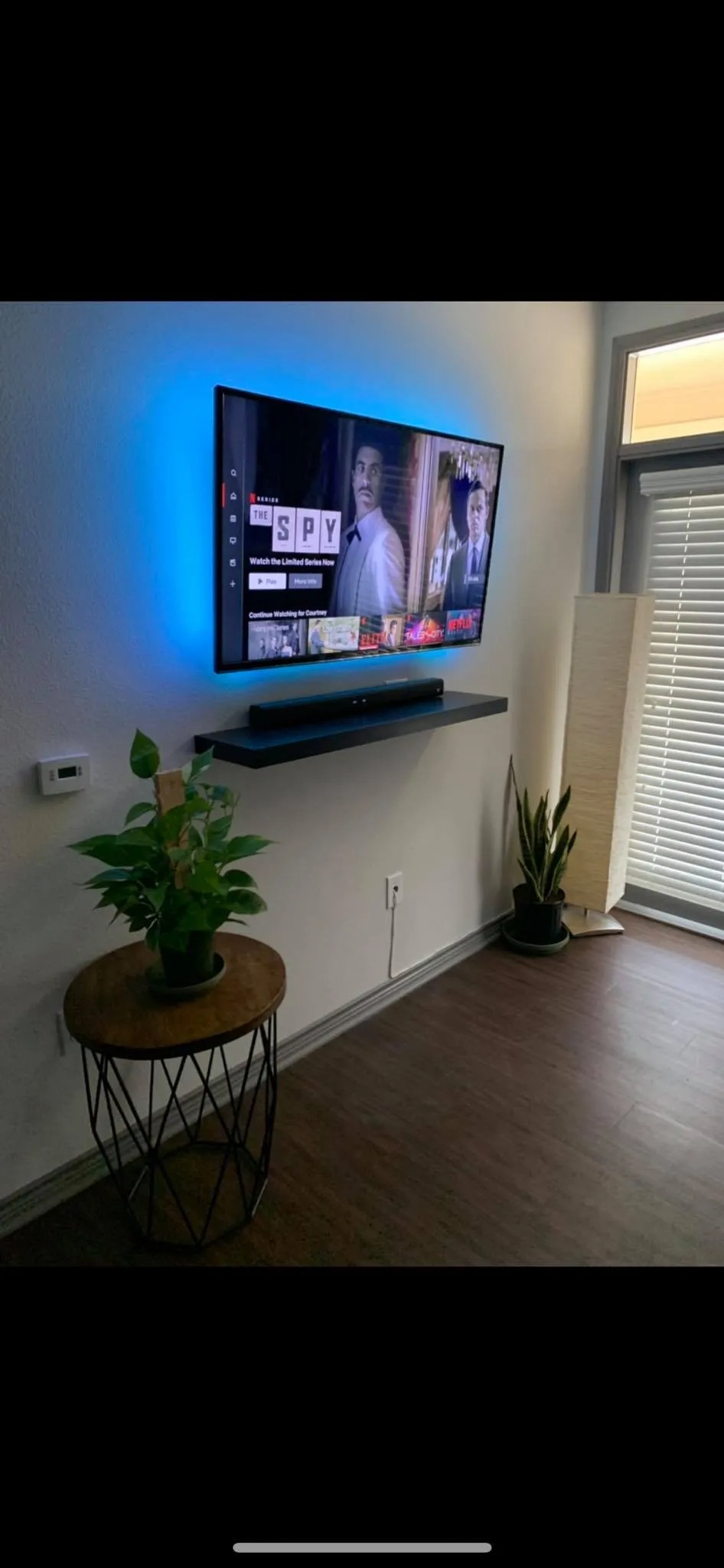 Wall-mounted TV with concealed cables and floating shelf below